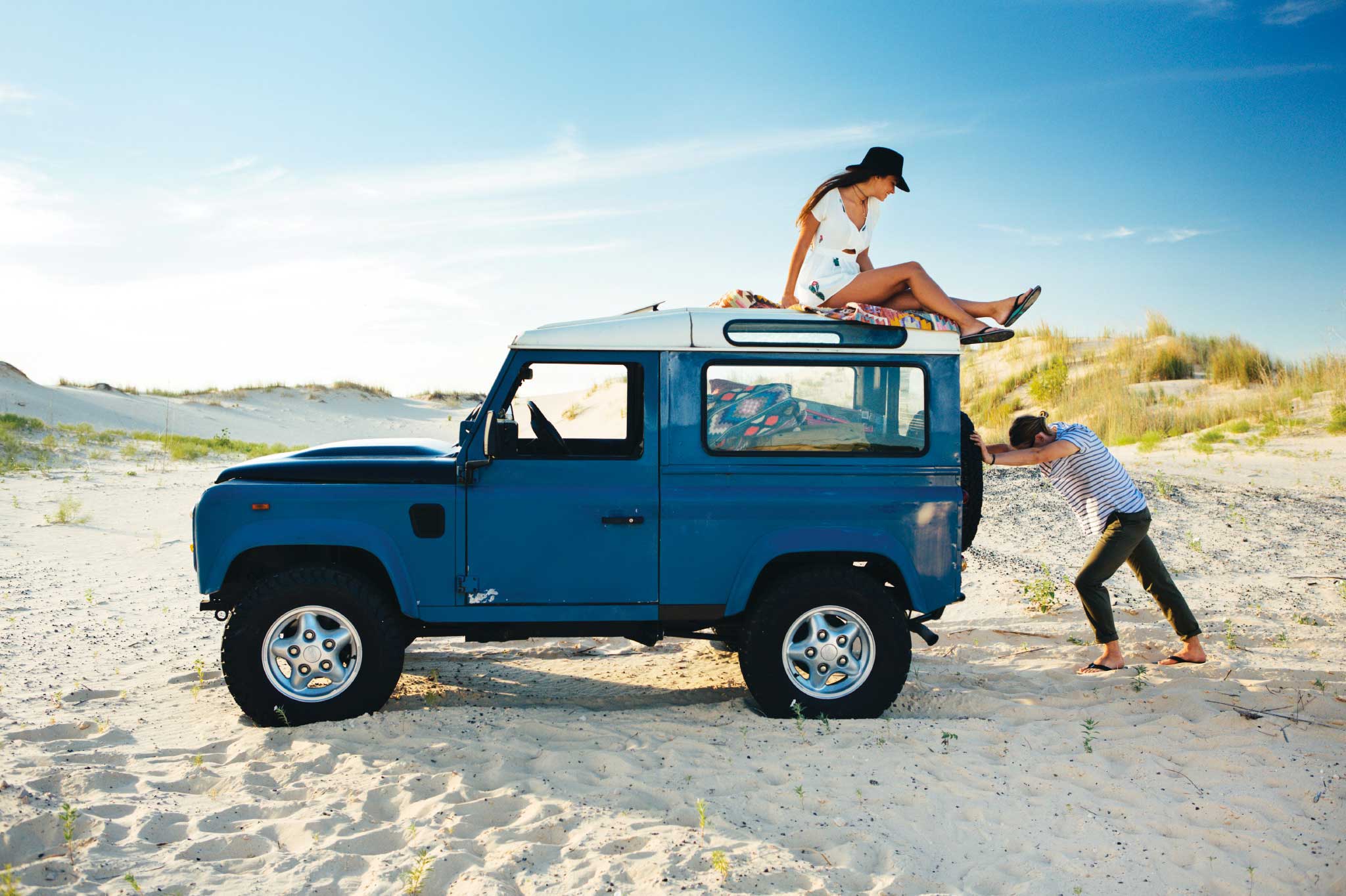 a man and woman on top of a blue car