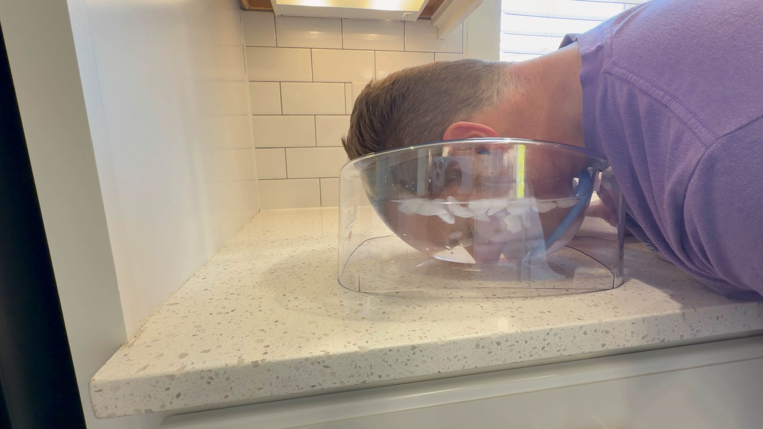 FaceTub face cold plunge therapy device with clear acrylic bowl and blue snorkel breathing mask on countertop for facial ice bath immersion and cold water therapy treatment